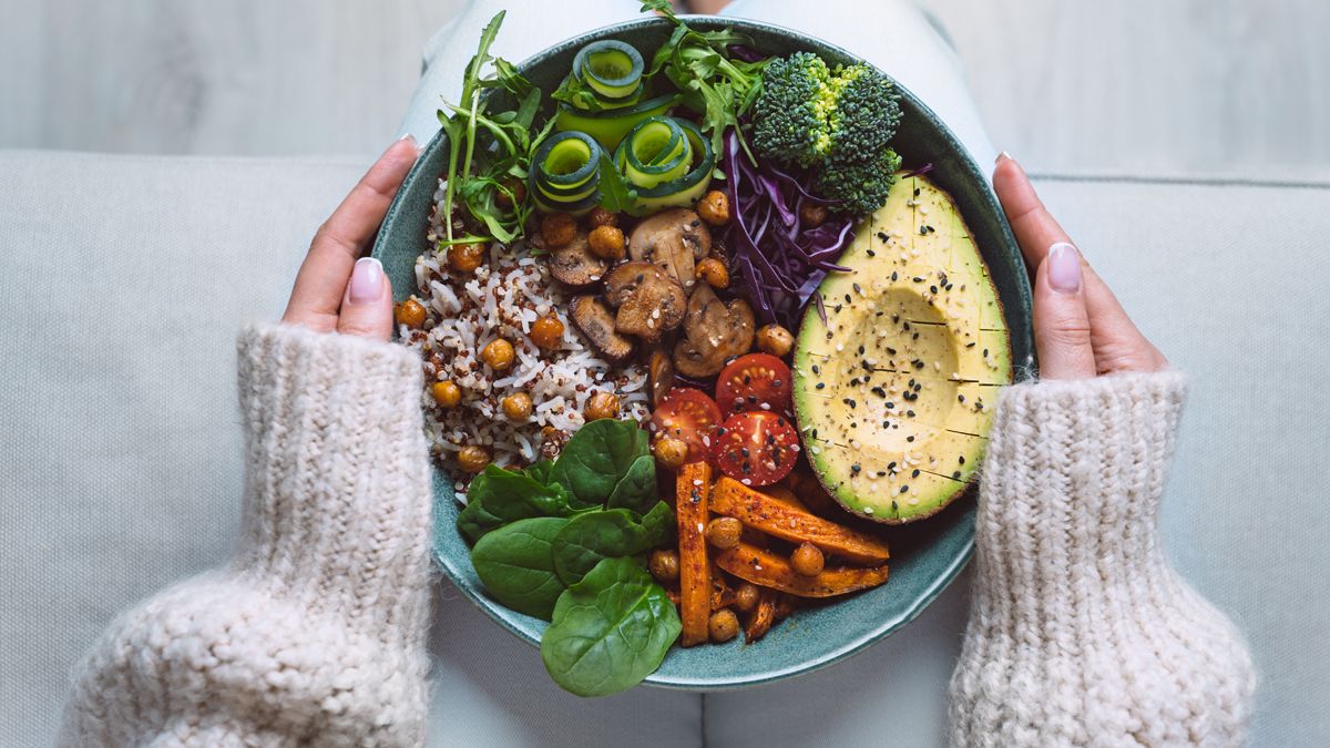 Hands holding a bowel of fruit, rice and vegetables, a diet that is typically associated with centenarians longevity.