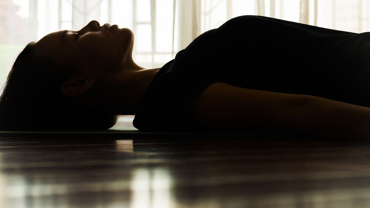 Person lying on floor in a calm, meditative state, symbolizing an ayahuasca healing experience.