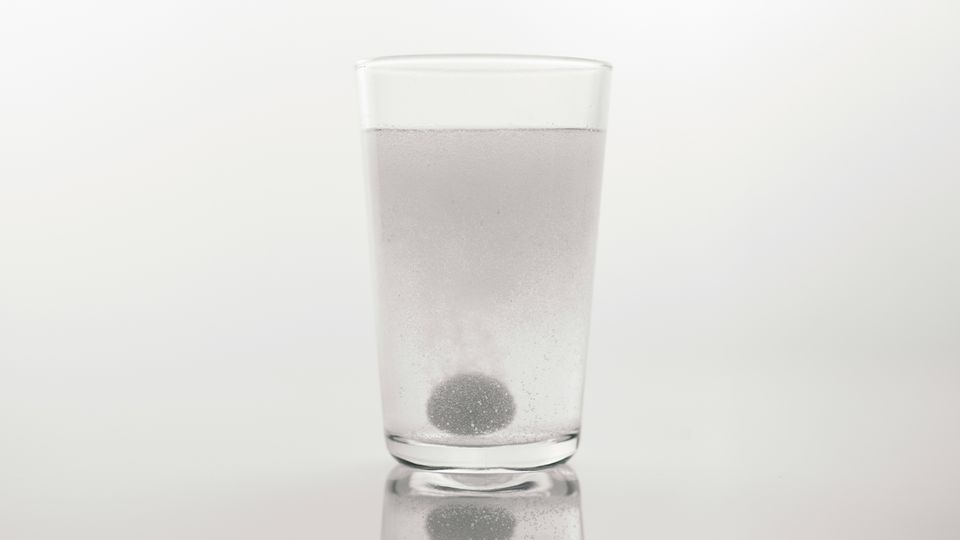A glass containing a tablet of baking soda dissolving in water for use as an antacid.