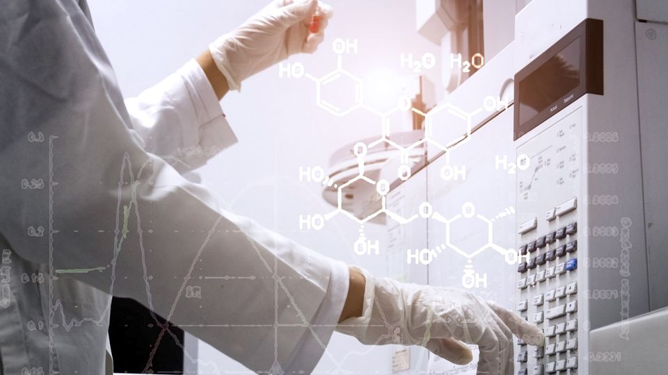 A researcher holds a sample in one hand and operates an instrument with the other.