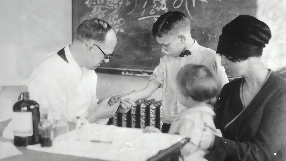 A black and white image of a doctor testing a child.