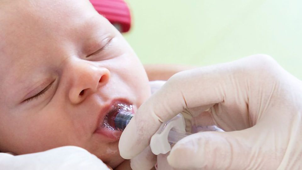 A doctor giving a baby an oral vaccine. 