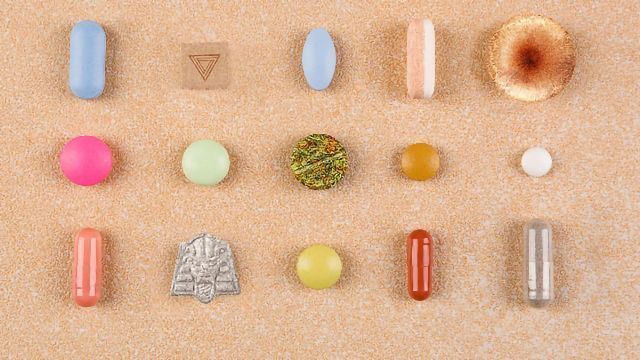A selection of psychedelics tablets of various shapes, colors and sizes laid out in a grid arrangement. 