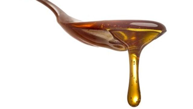 Honey dripping from a metal spoon. 