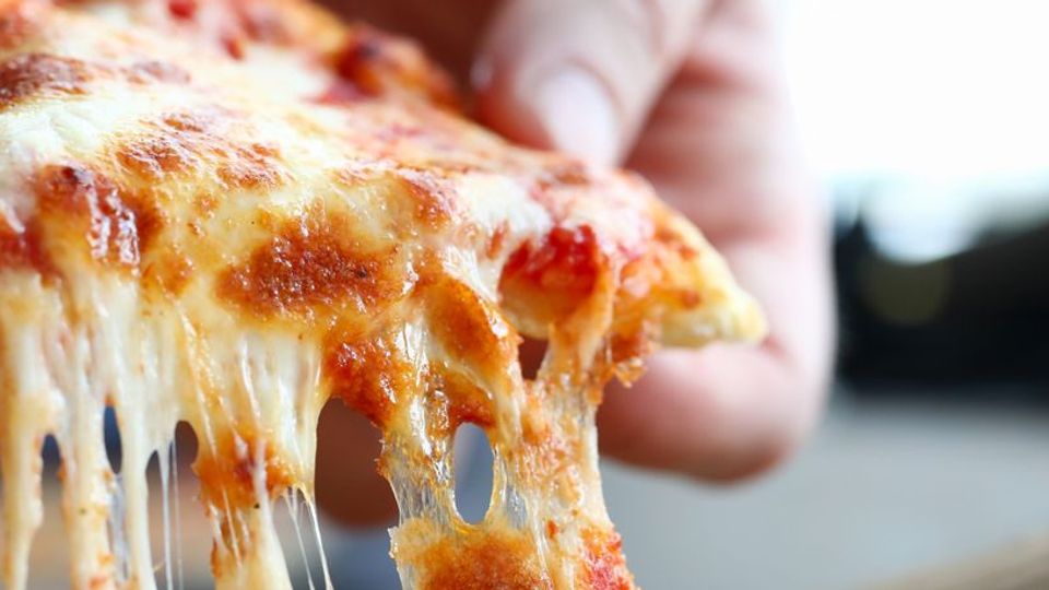 A close-up photo of a slice of pizza, cheese melting as it is lifted.