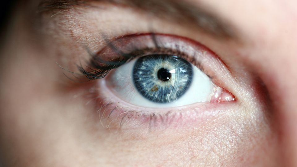 Close-up of a woman's eye with a light blue iris.