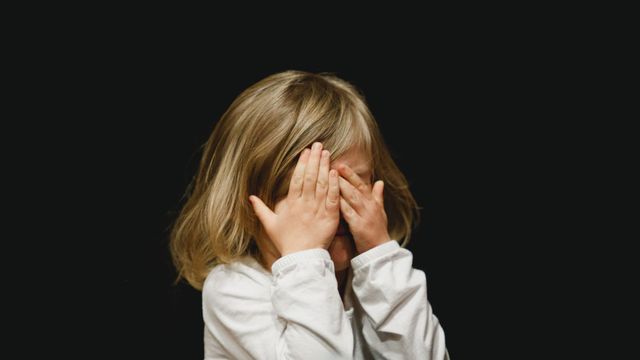 A child covers their eyes. 