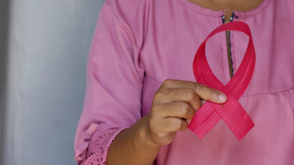 Woman holding a pink ribbon as an awareness of Breast Cancer Day.
