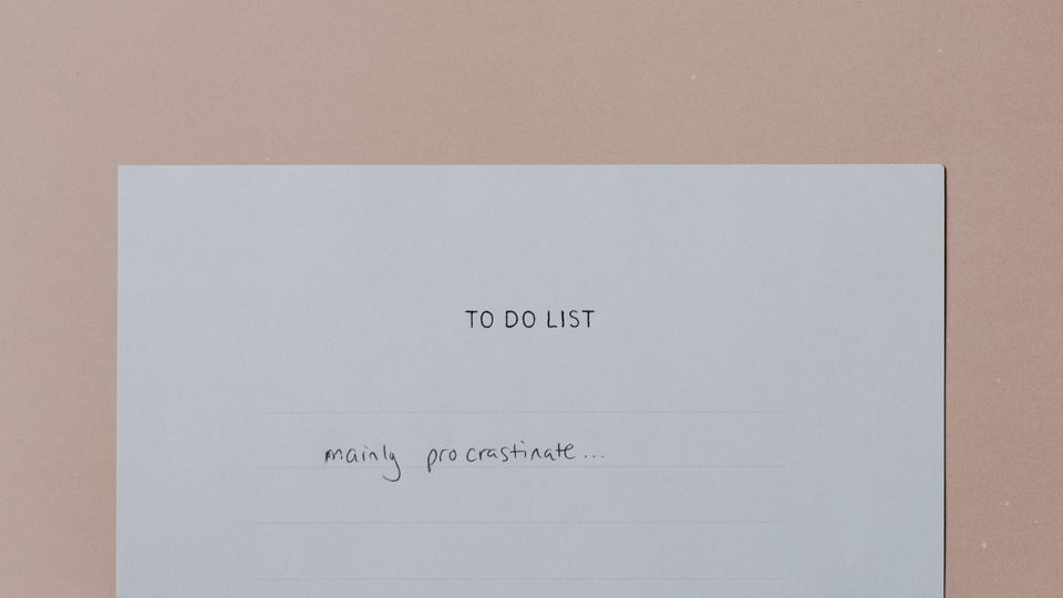 A piece of paper lying on a pink/brown background. The paper reads
