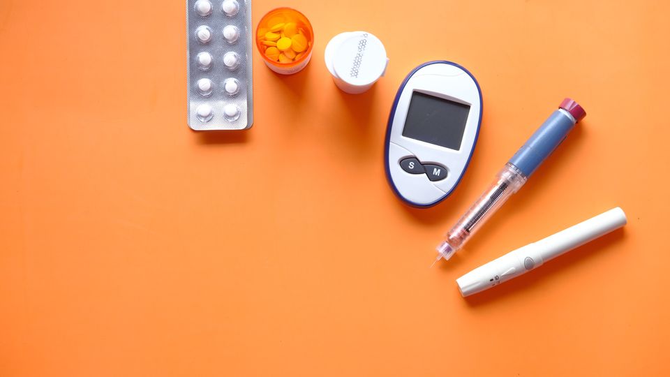Diabetes treatment paraphernalia on an orange background.