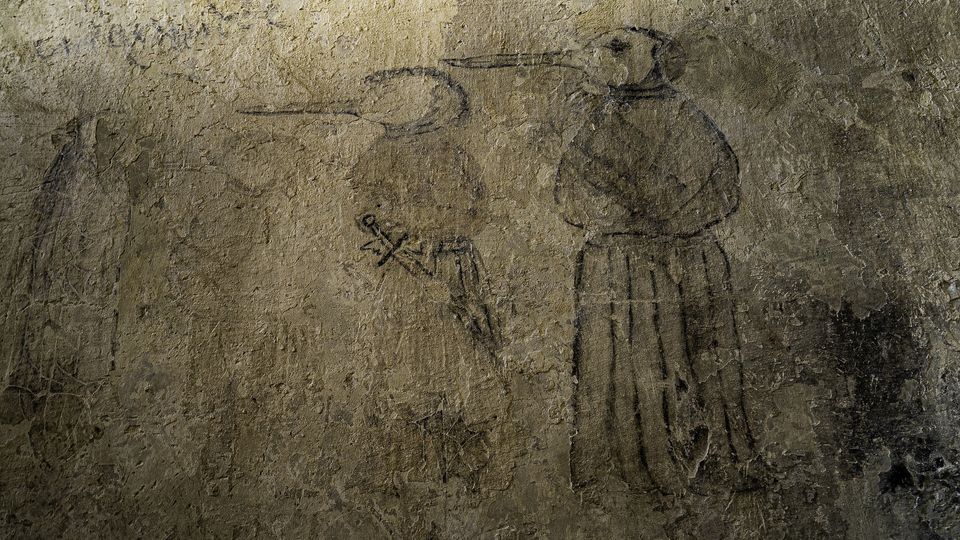 Drawings of a plague doctor on a wall.