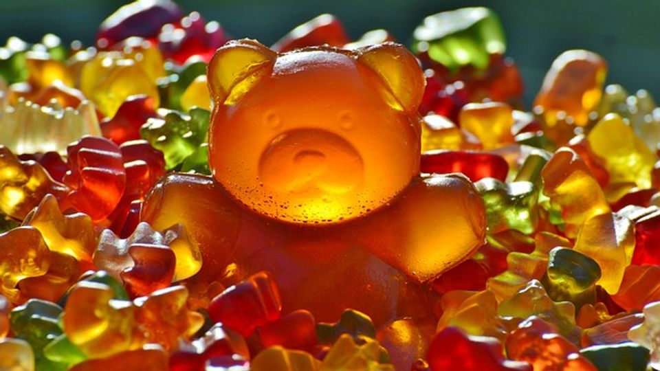 Multicolored gummy bears with one giant gummy in the middle.