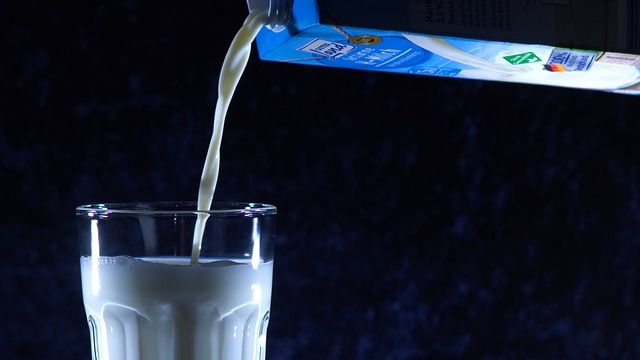 Milk being poured from a carton into a glass. 