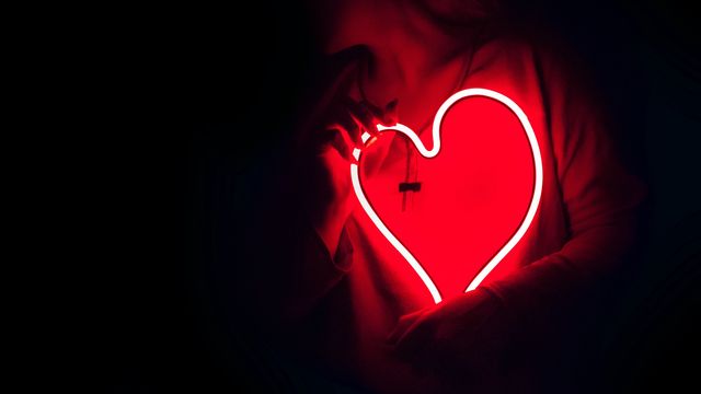 A person holding a neon heart. 