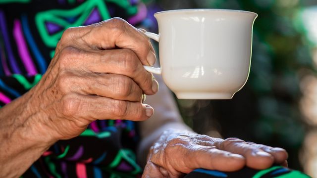 An older person holding a mug.