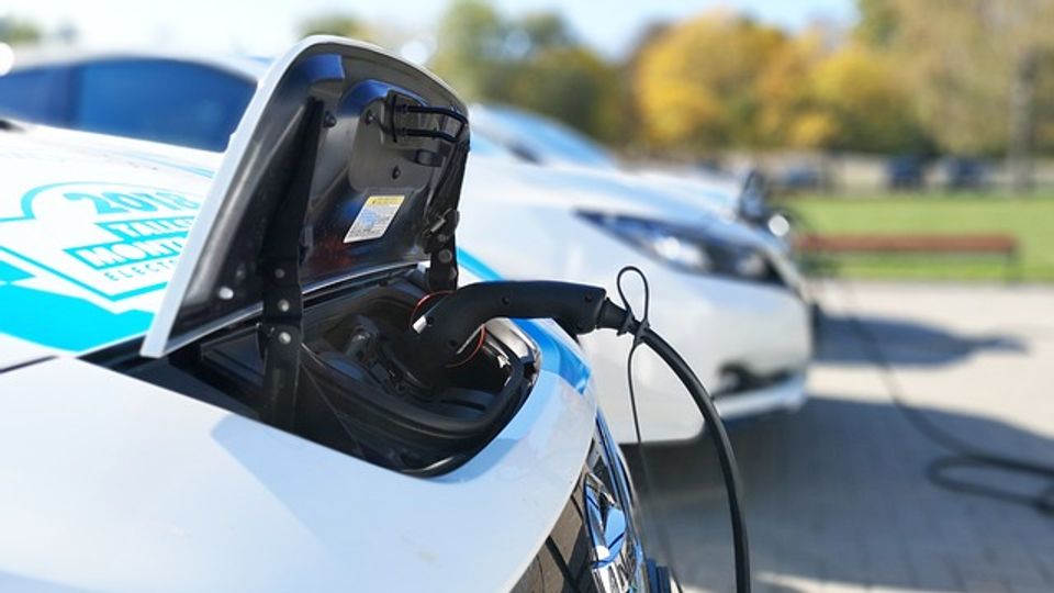 Front of an electric vehicle plugged into a charging cable.