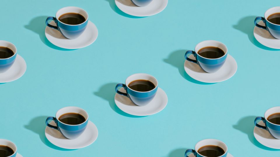 Several coffee cups on saucers, on a light blue background.