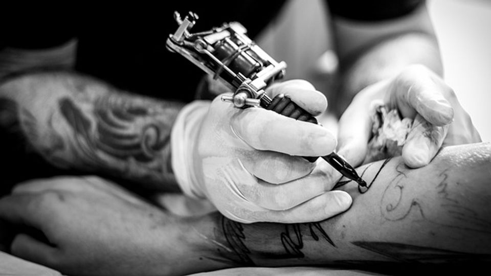 Person applying a tattoo to someone's arm.