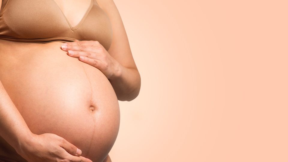 A pregnant woman holds her mid section.