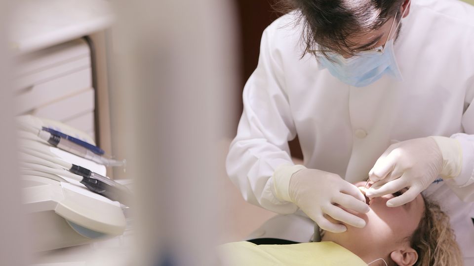 A dentist examines the mouth of a patient.