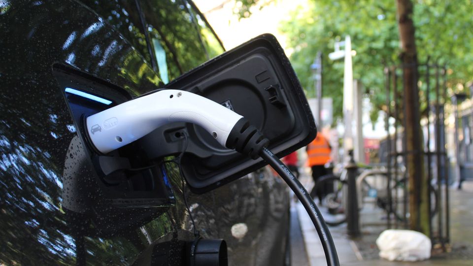 An electric vehicle charger, plugged into a car.