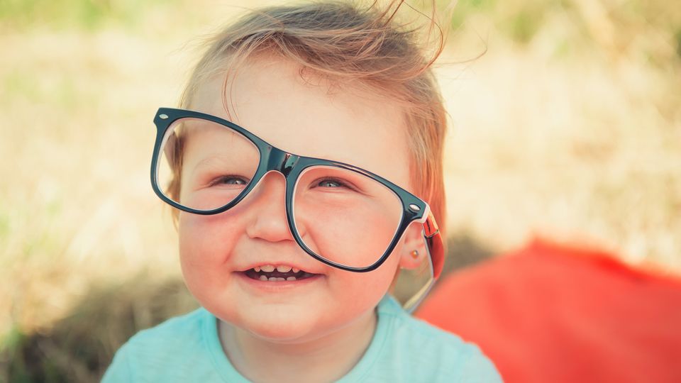 A toddler with glasses smiling.