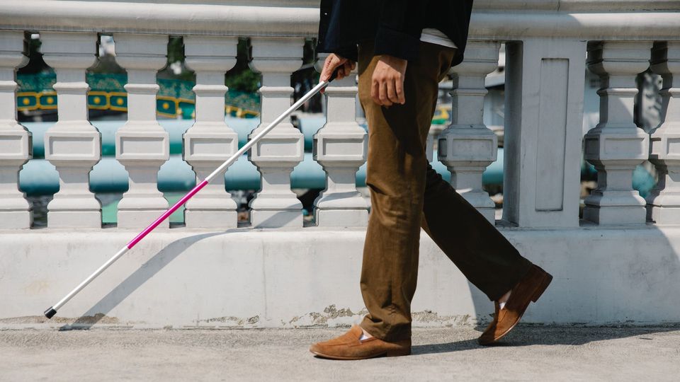 A blind man walks using a mobility cane.