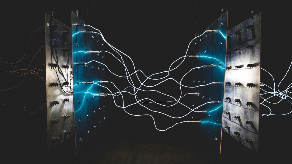 Two metal plates standing opposite each other, with light-up wires stretched between them to look like electricity. It is an approximate model of a capacitor.