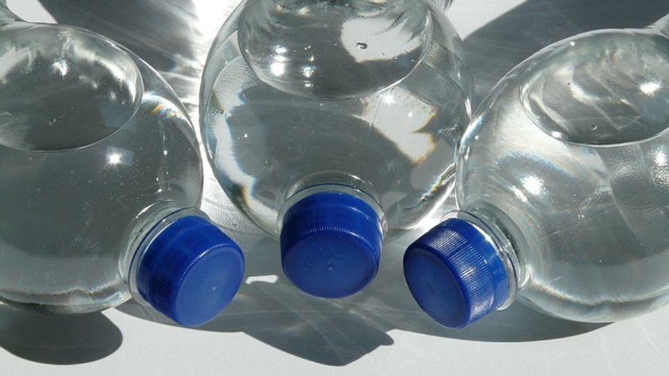 Three plastic bottles full of water on their sides with the lids pointing into the center.
