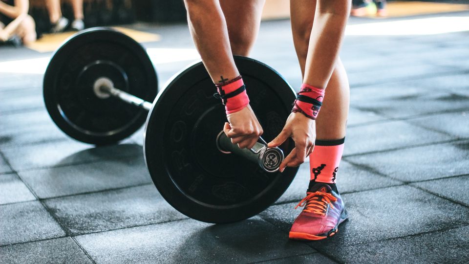 A woman adjusting a weight in the gym.