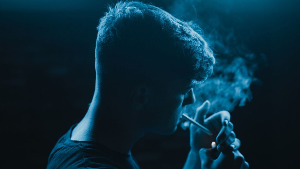 A man lighting a cigarette.