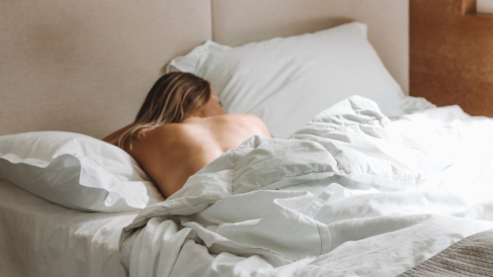 A woman face down laying in a bed.