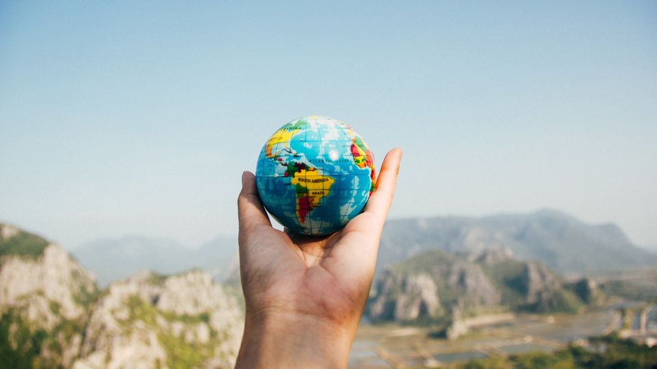 A small globe held in a hand.