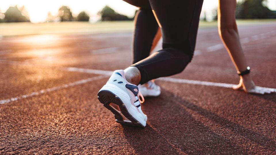 A woman poised to run at a racetrack.