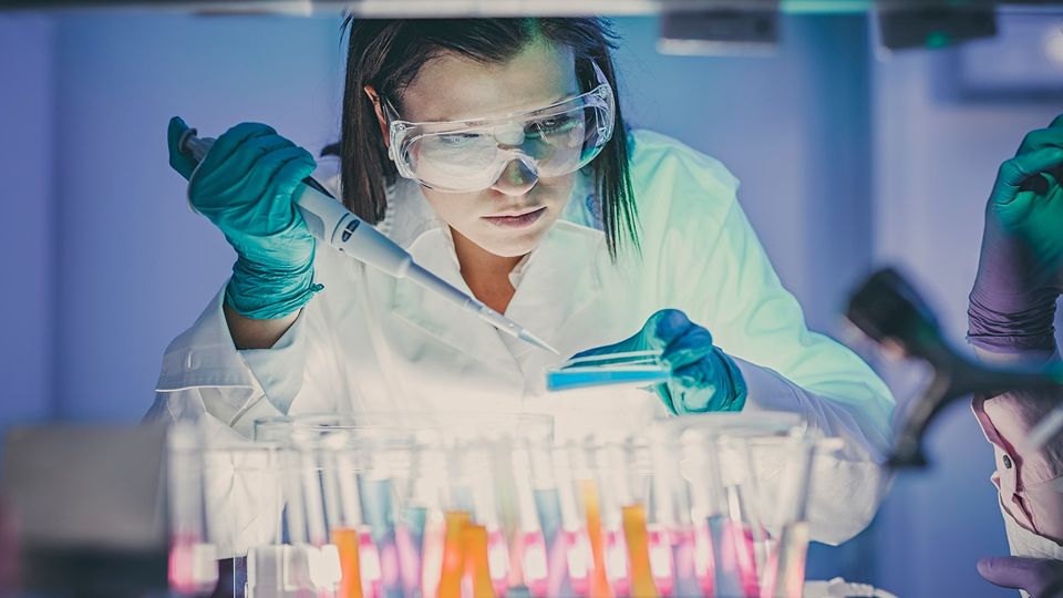 A lab worker pipetting a solution onto a plate.