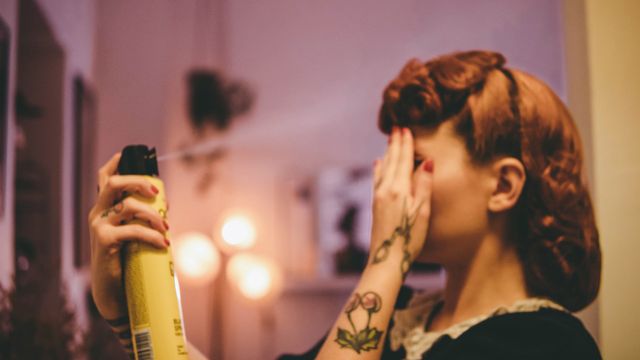 A woman hair spraying her hair. 