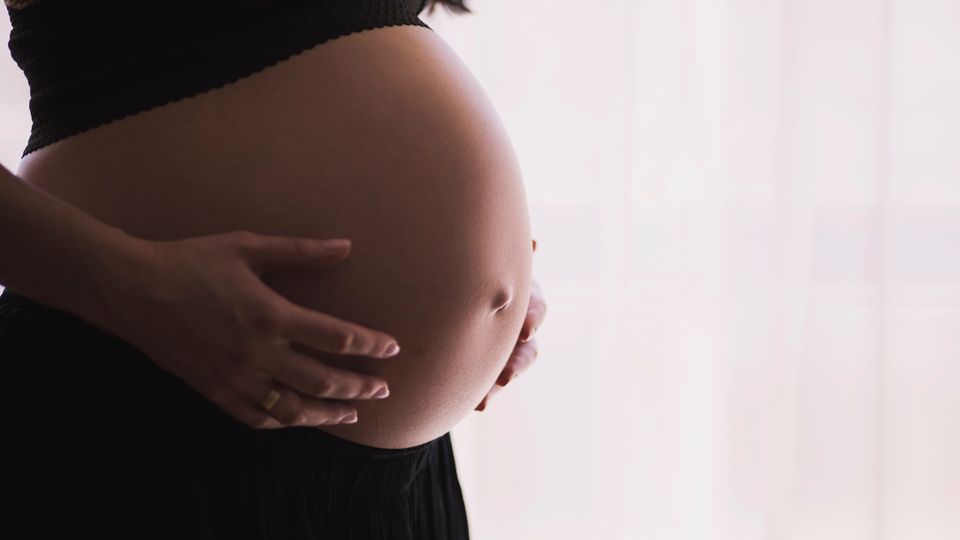 A pregnant woman holding her stomach.