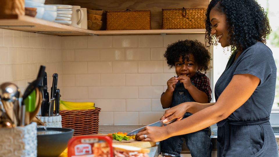 A mother cutting up food for her infant.