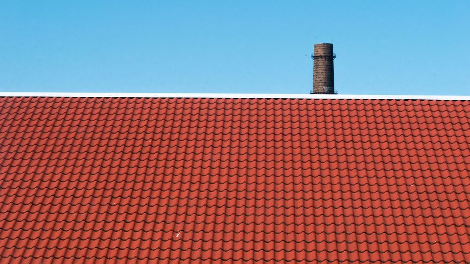 A roof with red tiles and a blue sky.