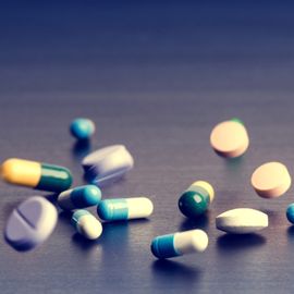 Various oral medicines falling onto a tabletop. 
