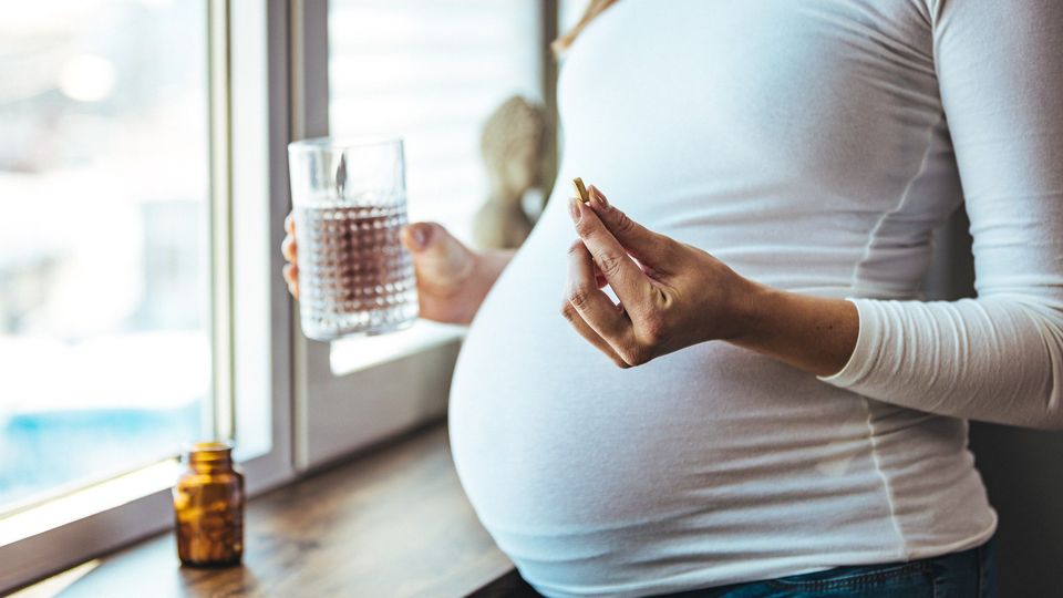 A pregnant woman taking a tablet.