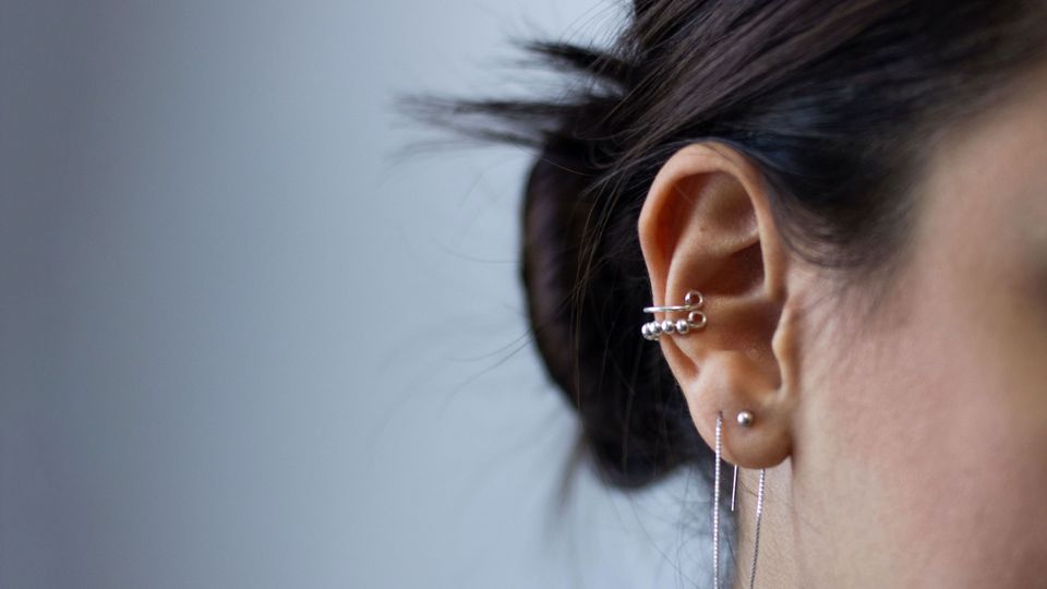 A person's ear, decorated with jewellery.