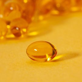 A gold-colored capsule on a yellow background. 