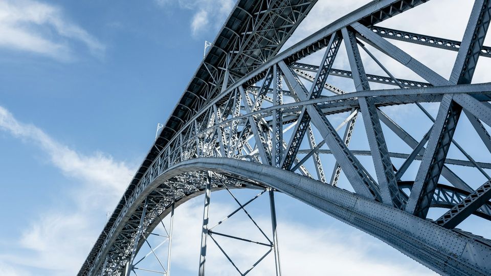 A low-angle photograph of a steel arch bridge in Porto, Portugal.