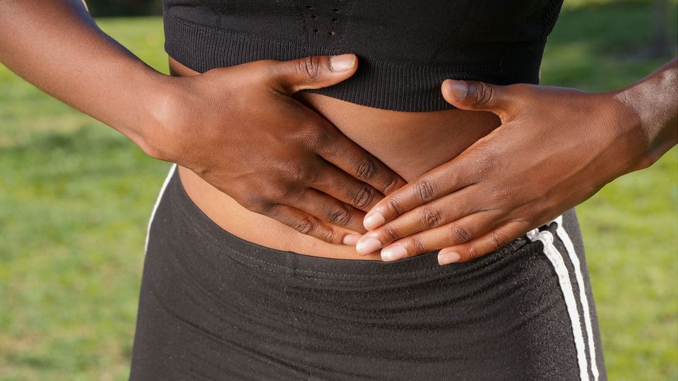 A person in exercise wear holds their stomach.
