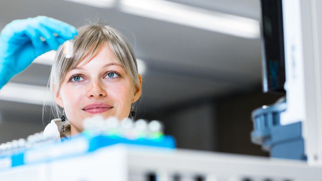 A scientist holding a vial. 