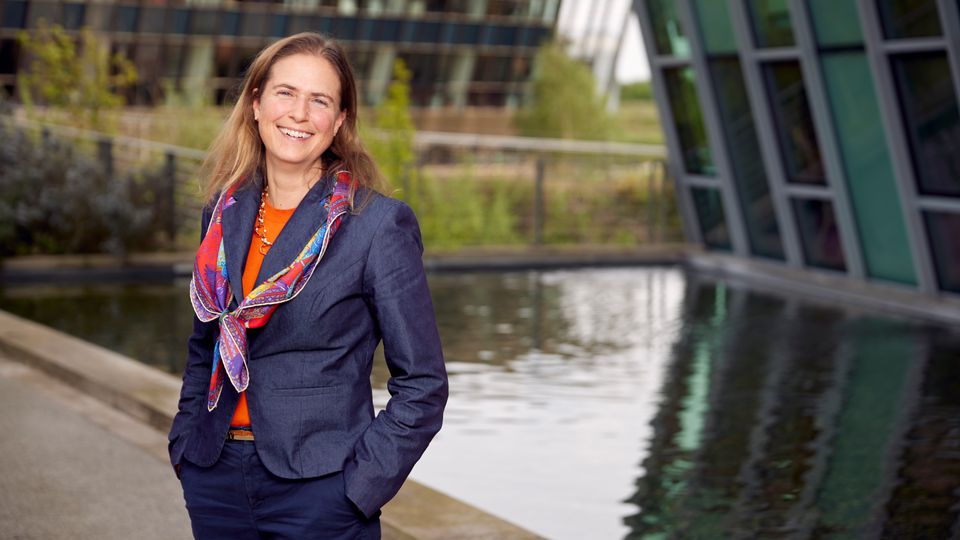 Dr. Sarah Teichmann standing next to a building and pond.