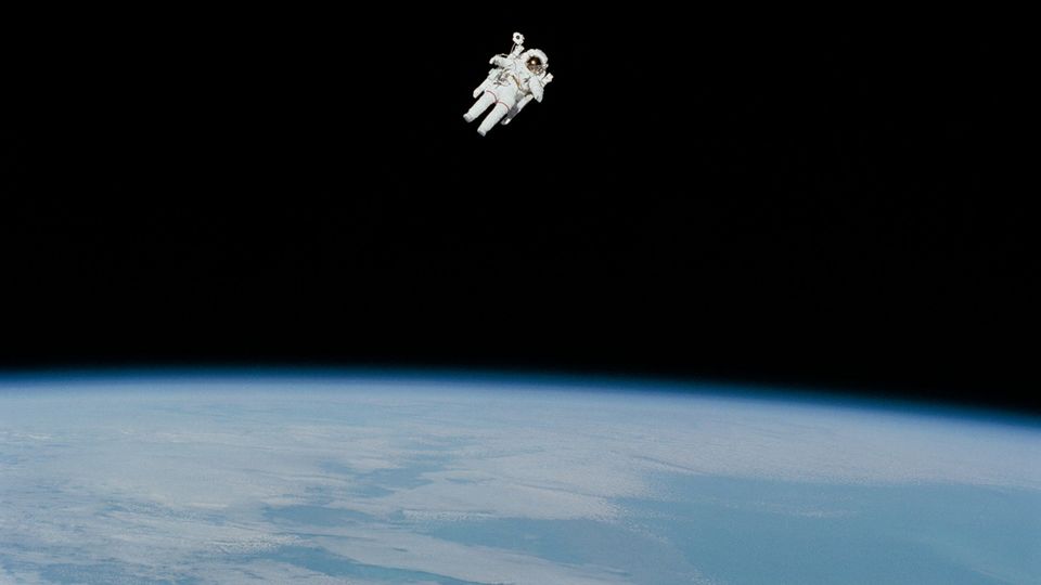 An astronaut floating in space above earth.