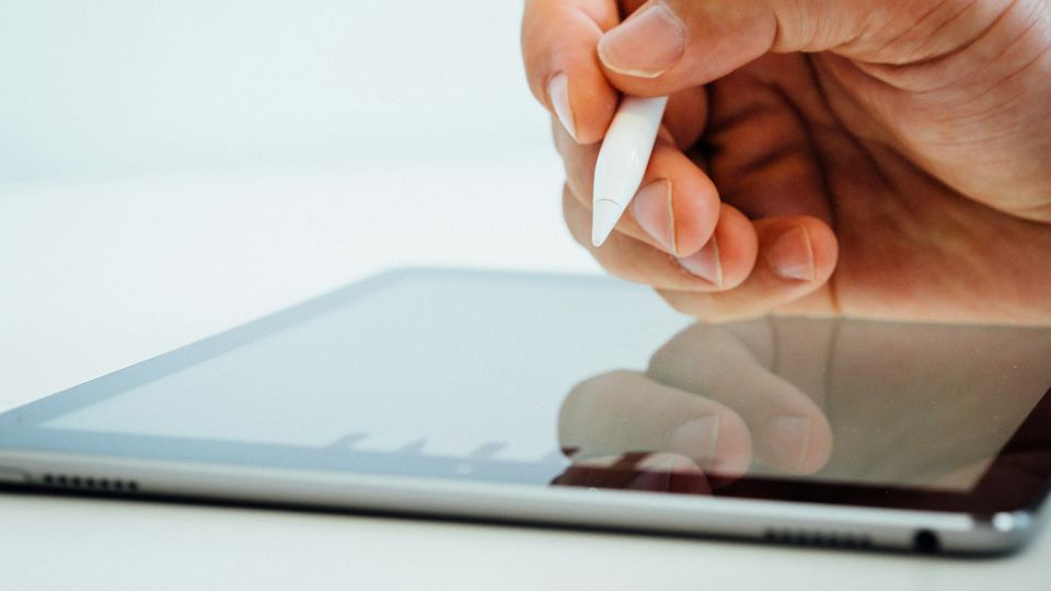 A close up of someone writing on an ipad.