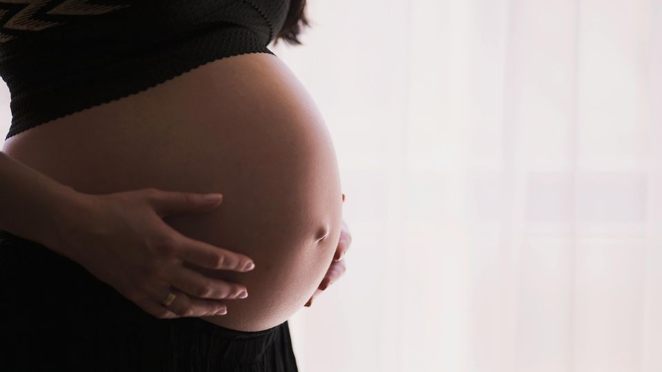 Photograph of a pregnant woman holding her stomach